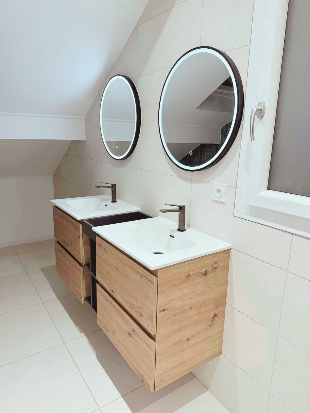 alle de bain contemporaine avec double vasque suspendue en bois, miroir LED rond et carrelage mural clair – Rénovation AK dans le Pays de Gex